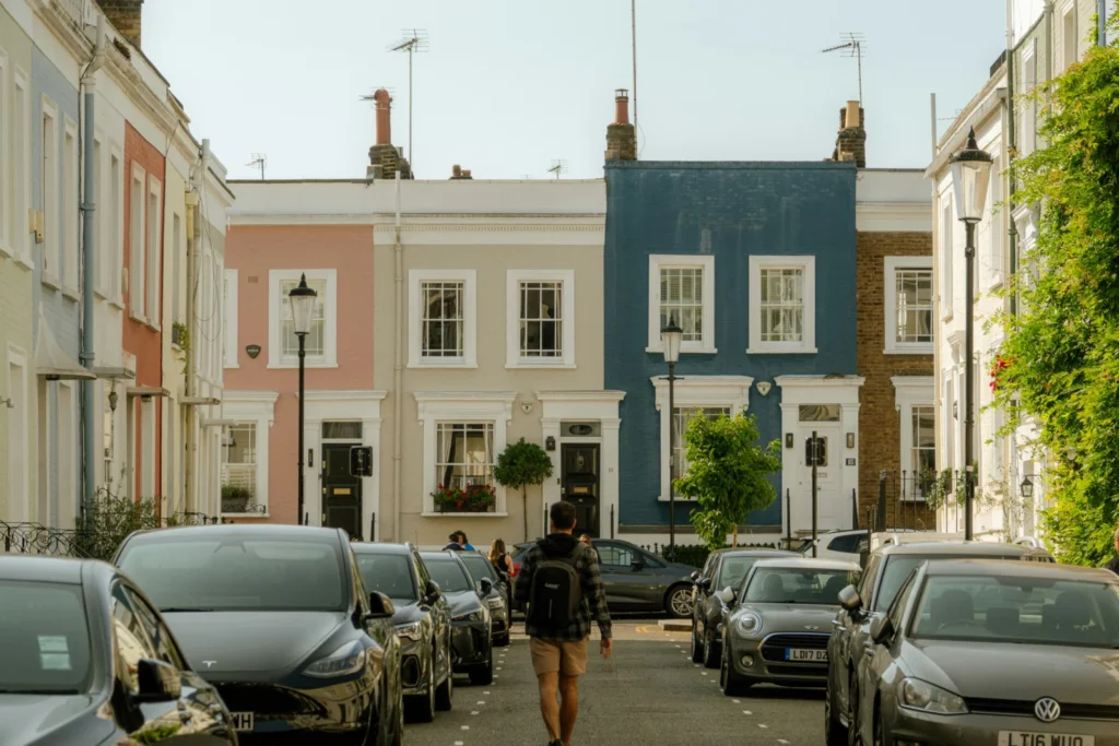 Person walking down a street lined with parked cars, representing homeowners weighing early repayment charges on a product transfer