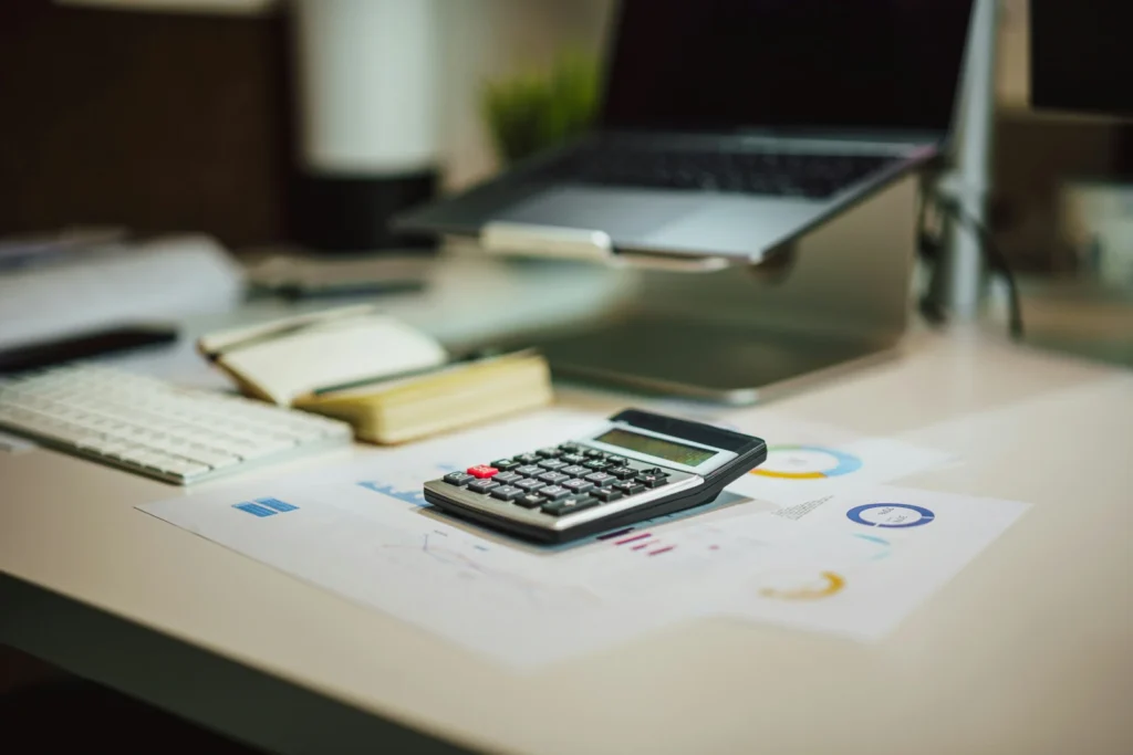 Calculator next to a laptop on a table, used to compare new mortgage rates when a fixed rate ends