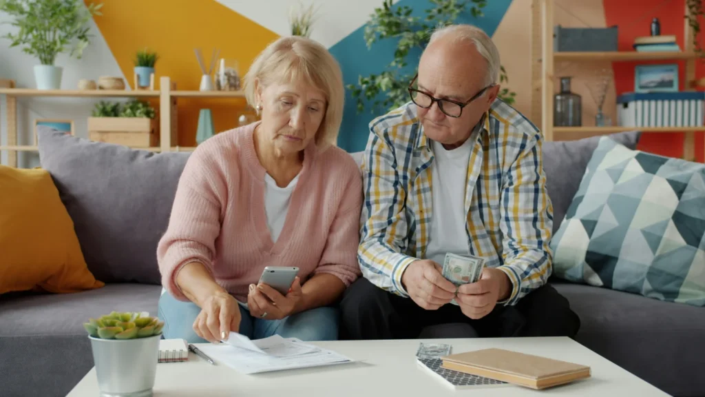 Older couple looking at bills and a phone while their fixed rate mortgage is ending