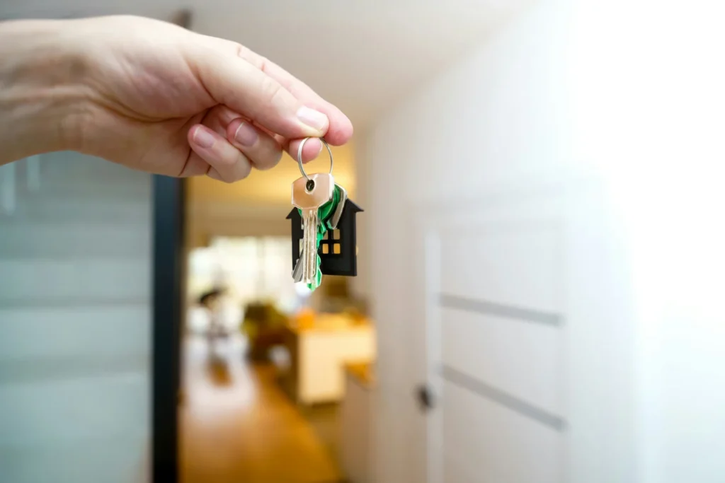 Person holding house keys at a front door, representing getting advice on a mortgage product transfer