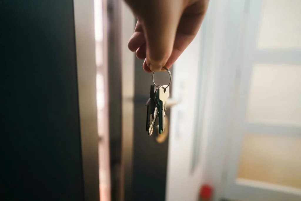 Hand holding a keyring near an open door, representing getting help to renew a mortgage